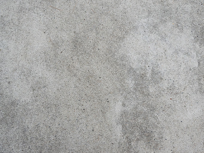 Weathered gray concrete wall texture with subtle stains, speckles, and faint vertical discoloration
