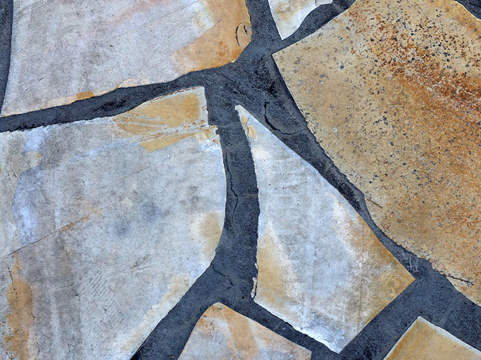 Close-up of irregular beige flagstone patio with dark mortar lines and textured surface