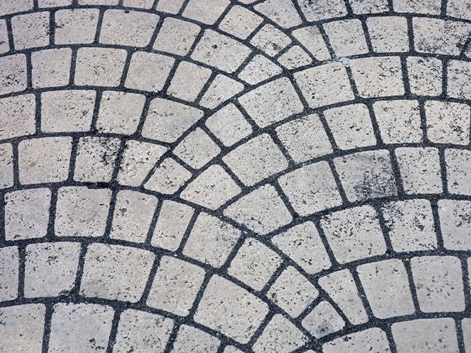 Gray cobblestone pavement with overlapping semicircular radial pattern and dark grout